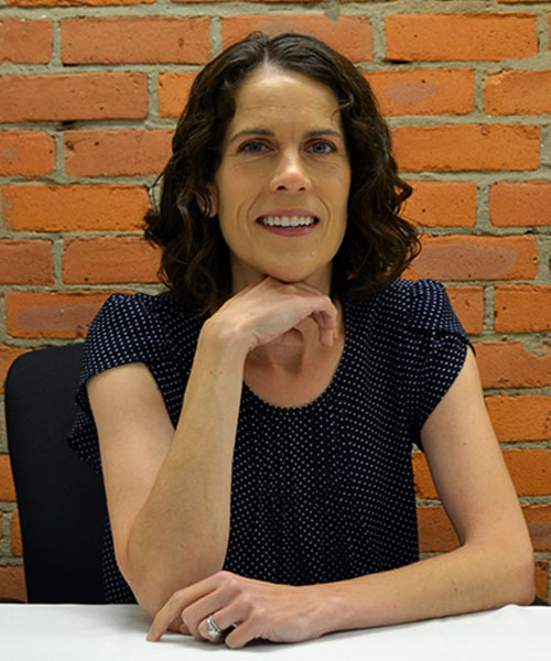Staff headshot Alison Richardson, in front of a brick background.