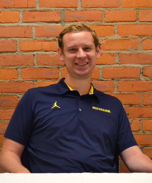 Staff headshot Connor Flynn, in front of a brick background.