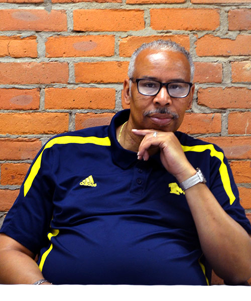Staff headshot Kevin Perkins, in front of a brick background.
