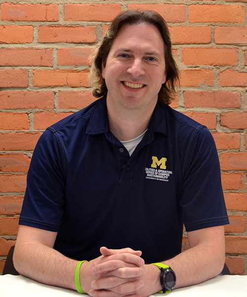 Staff headshot Nicholas Thornton, in front of a brick background.