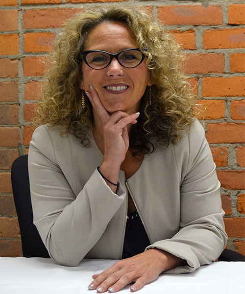 Staff headshot Amy Webb, in front of a brick background.