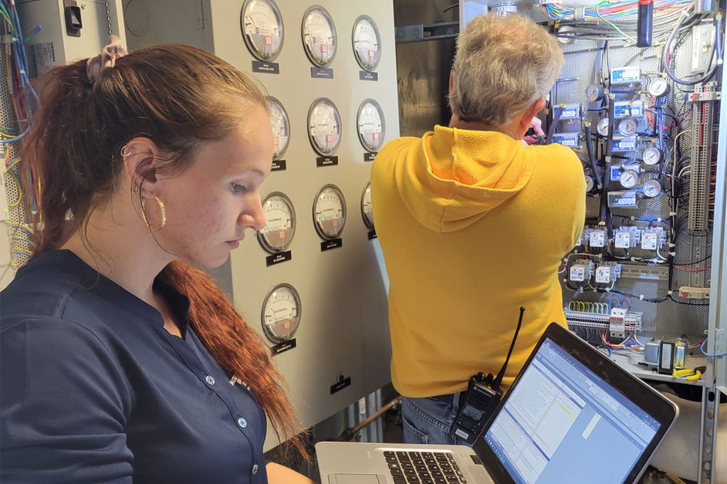 An OCS Intern and DDC Technician perform maintenance on an air handler control panel.
